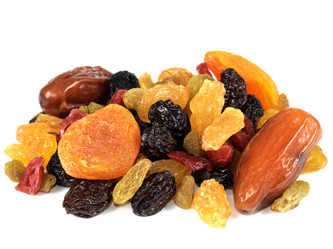 a DSLR royalty free digital image of a mixed selection of juicy looking dried fruits, including raisins, sultanas, dates, currants, apricots, isolated against a plain white background